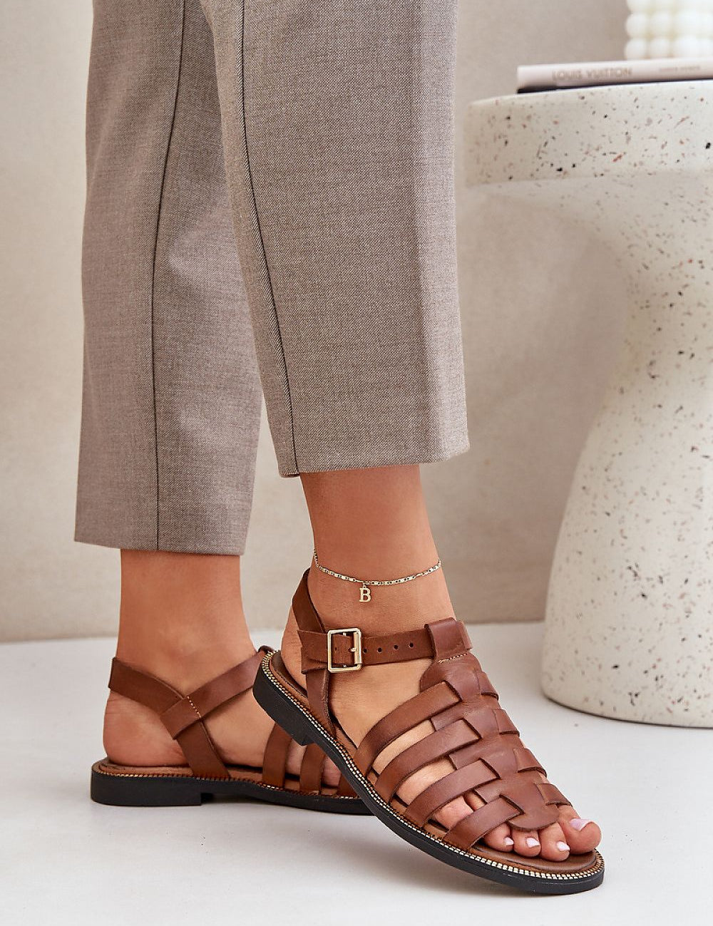 Woman wearing Celira Flat Leather Sandals with ankle strap and buckle, showcasing casual elegance and genuine leather craftsmanship.