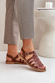 Woman wearing Avelisse leather flat sandals with adjustable buckle, showcasing versatile style and comfort with gray pants.