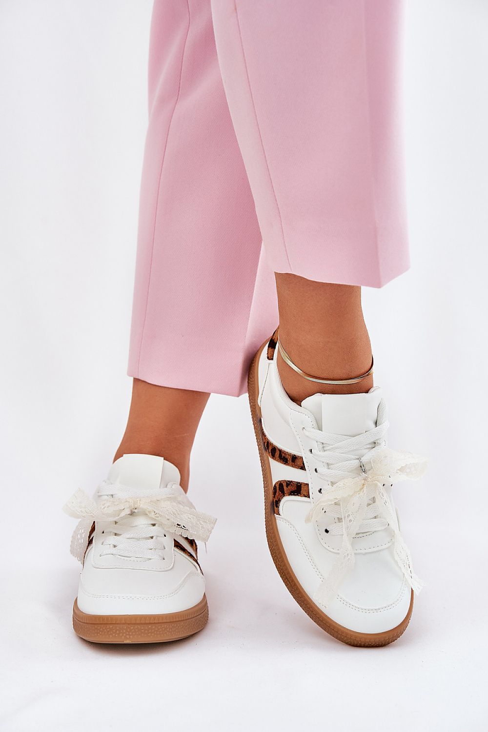 Alt Tag: Woman wearing pink pants and white Zyrmira Custom Lace Sport Sneakers with eco leather and lace accents.