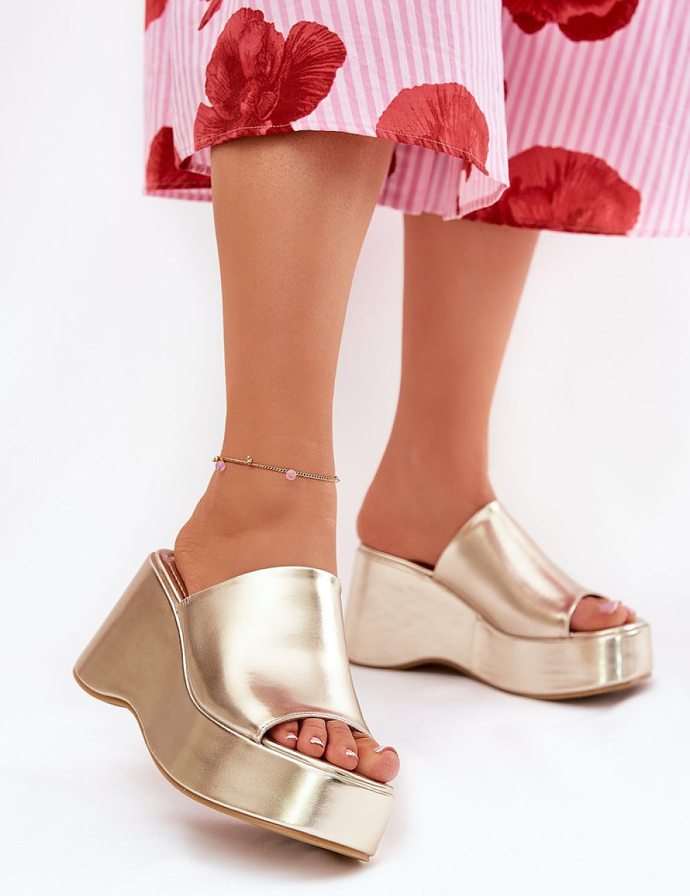 Selentia faux leather wedge sandals with open-toe design and sleek gold finish, paired with a floral skirt for modern elegance.