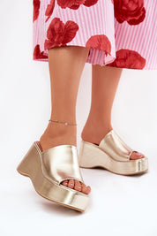 Selentia faux leather wedge sandals with open-toe design and sleek gold finish, paired with a floral skirt for modern elegance.