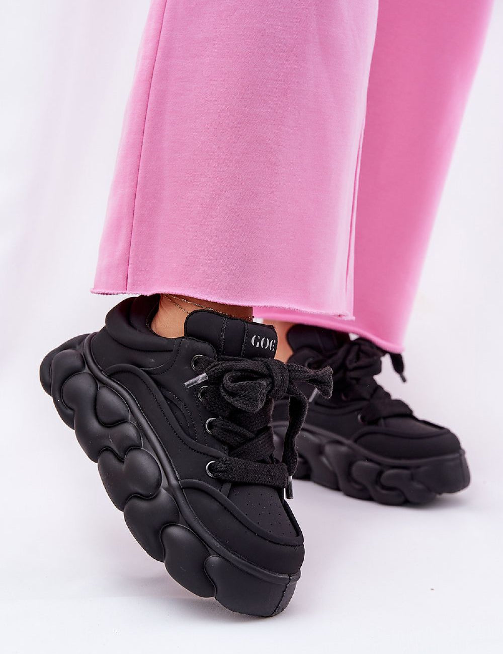 Black Vernesse Elevated Leather Sport Shoes with thick lacing and platform sole, paired with pink pants for a bold fashion look.