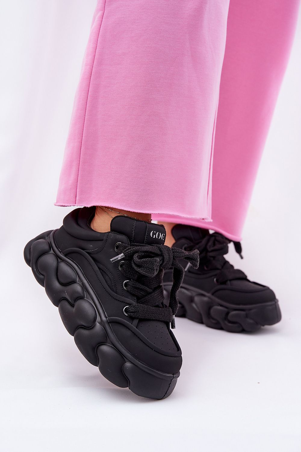 Black Vernesse Elevated Leather Sport Shoes with thick lacing and platform sole, paired with pink pants for a bold fashion look.
