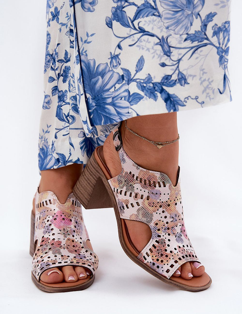 Woman wearing floral dress and pink patterned sandals with block heels.