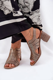 Woman wearing stylish open-toe heeled sandals with cut-out design, paired with floral print pants.