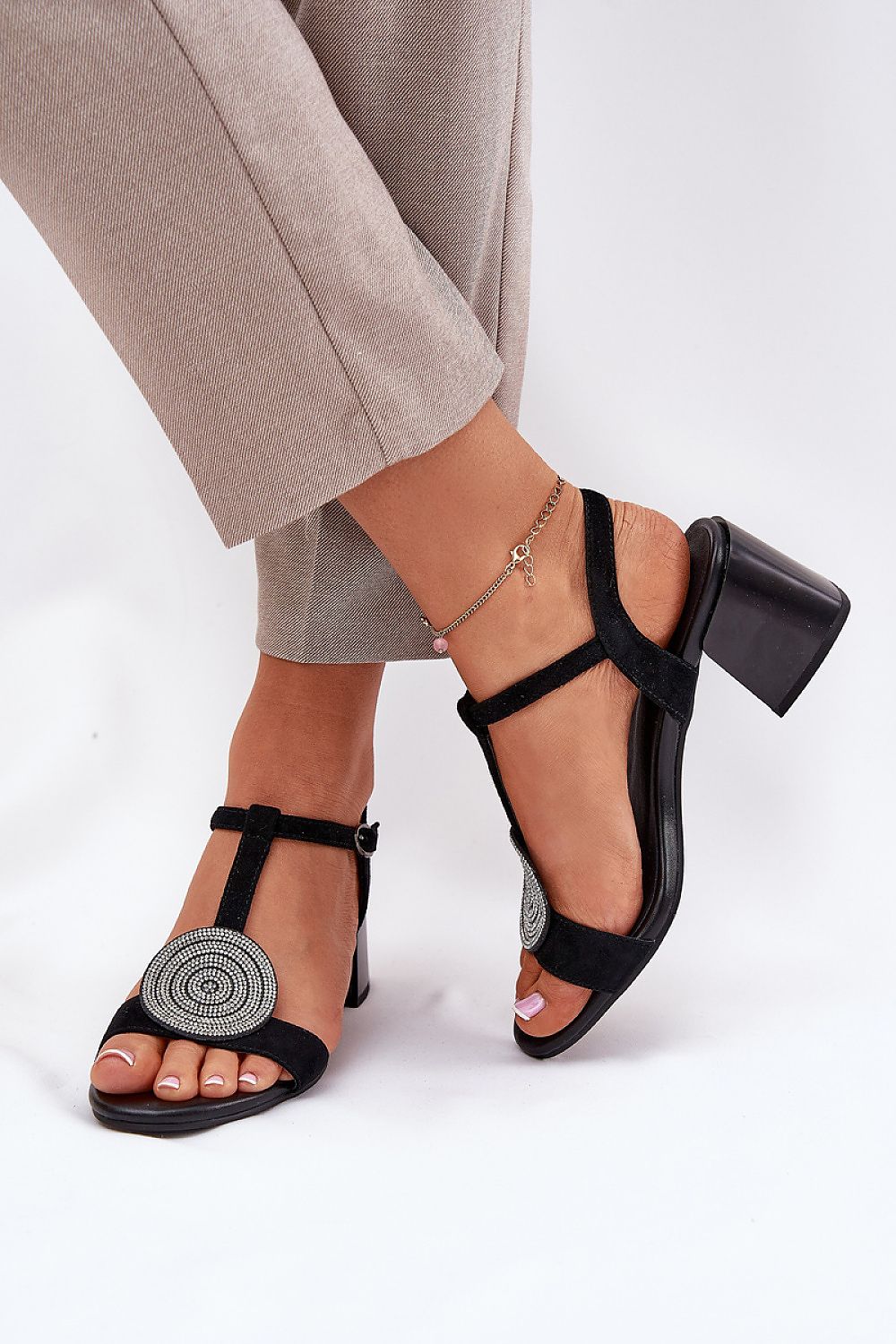 Evelenne leather sandals with sculpted heel and ankle strap, featuring a modern front accent, worn with beige trousers.
