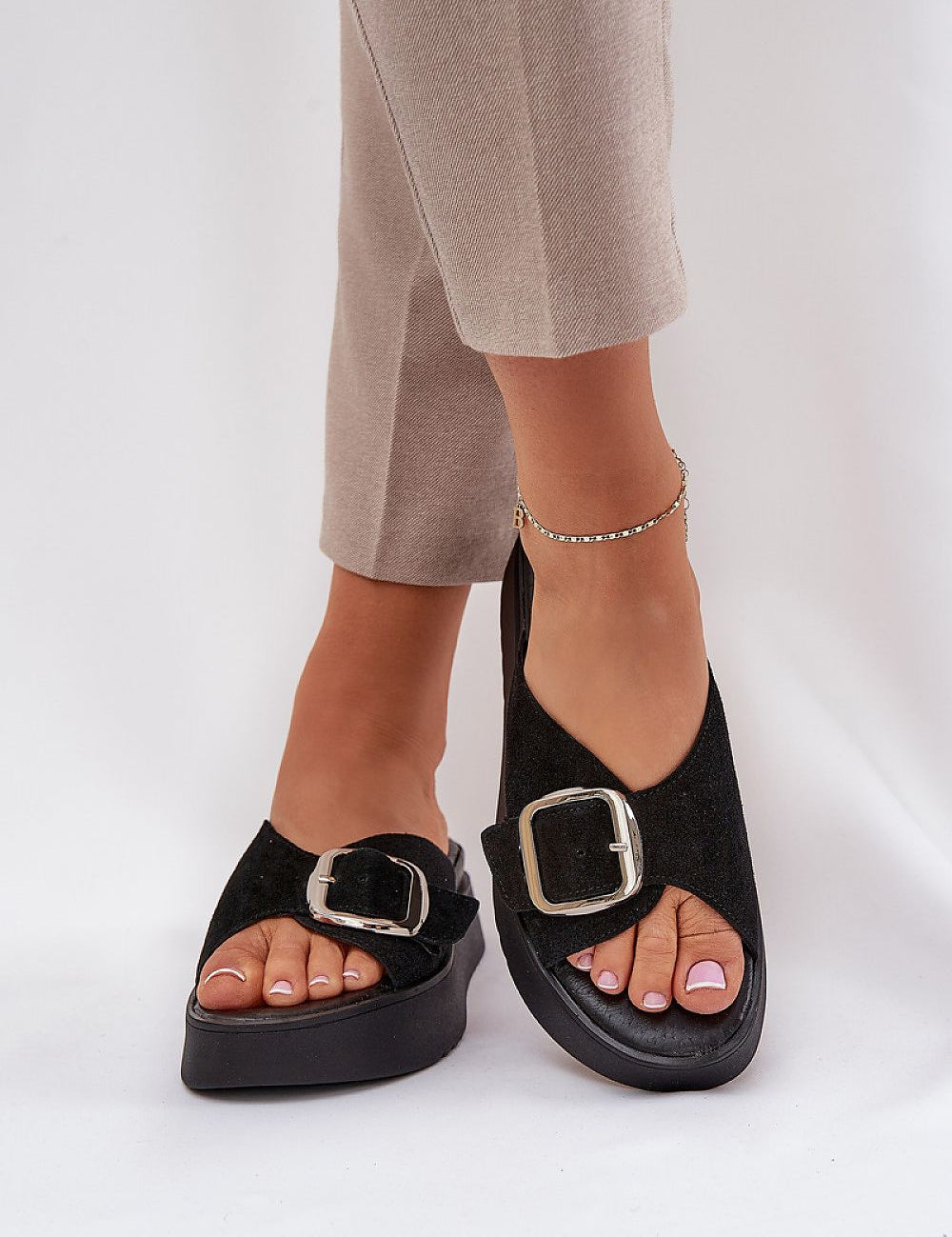Woman wearing black Solva suede platform slides with bold front buckle and cushioned insole for stylish comfort.