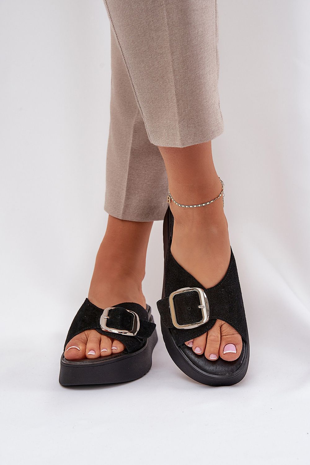 Woman wearing black Solva suede platform slides with bold front buckle and cushioned insole for stylish comfort.