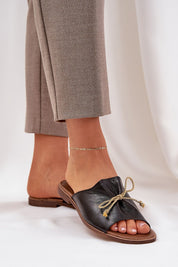 Veletta Soft Bow Sandals in black leather with delicate bow detail, worn with beige pants, showcasing elegance and summer style