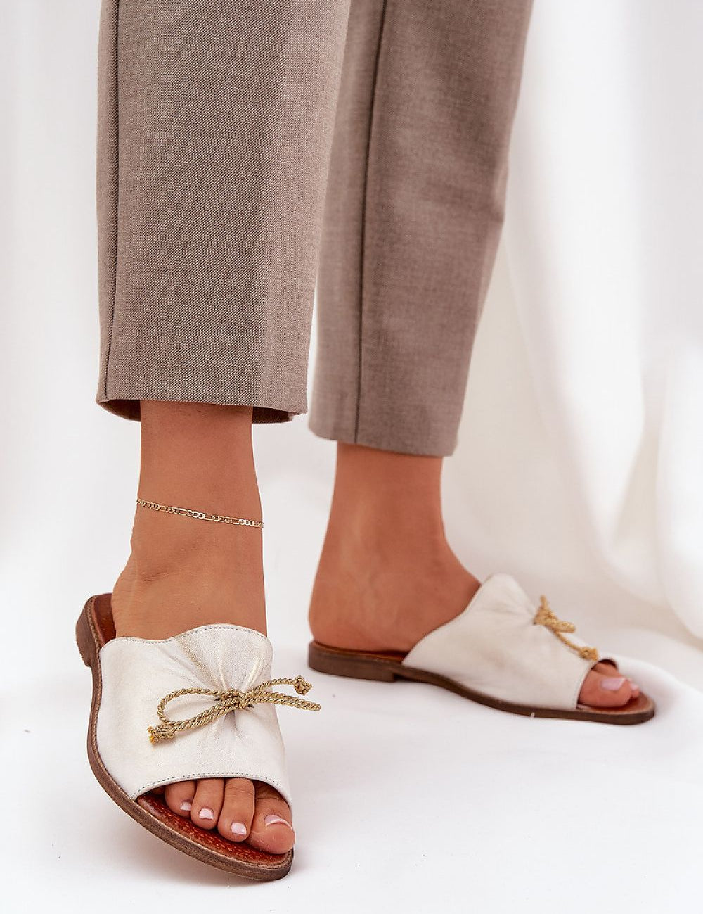 Veletta Soft Bow Sandals in natural leather with delicate bow and ruched design, ideal for summer, worn with beige pants and anklet.
