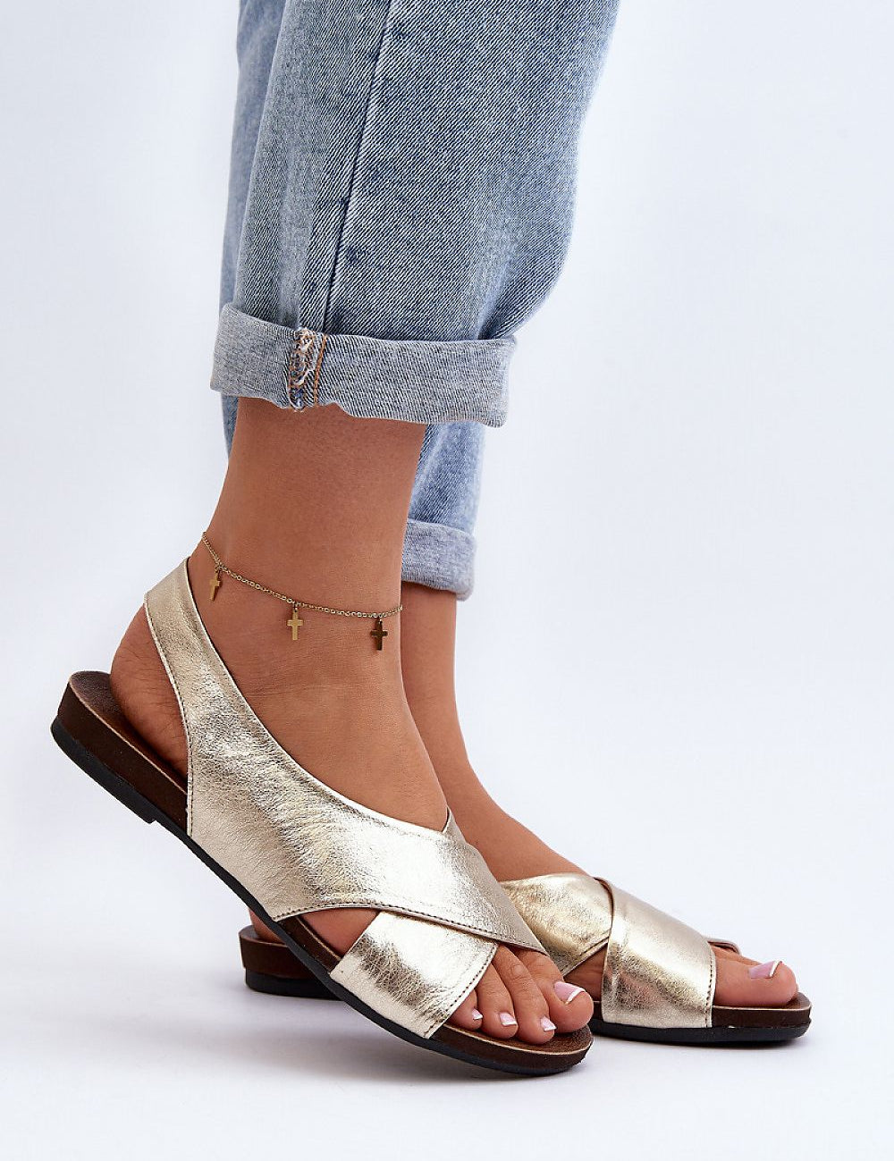 Woman wearing Talmea Soft-Strap Leather Sandals in metallic gold, paired with rolled-up jeans, showcasing open toe and heel design.