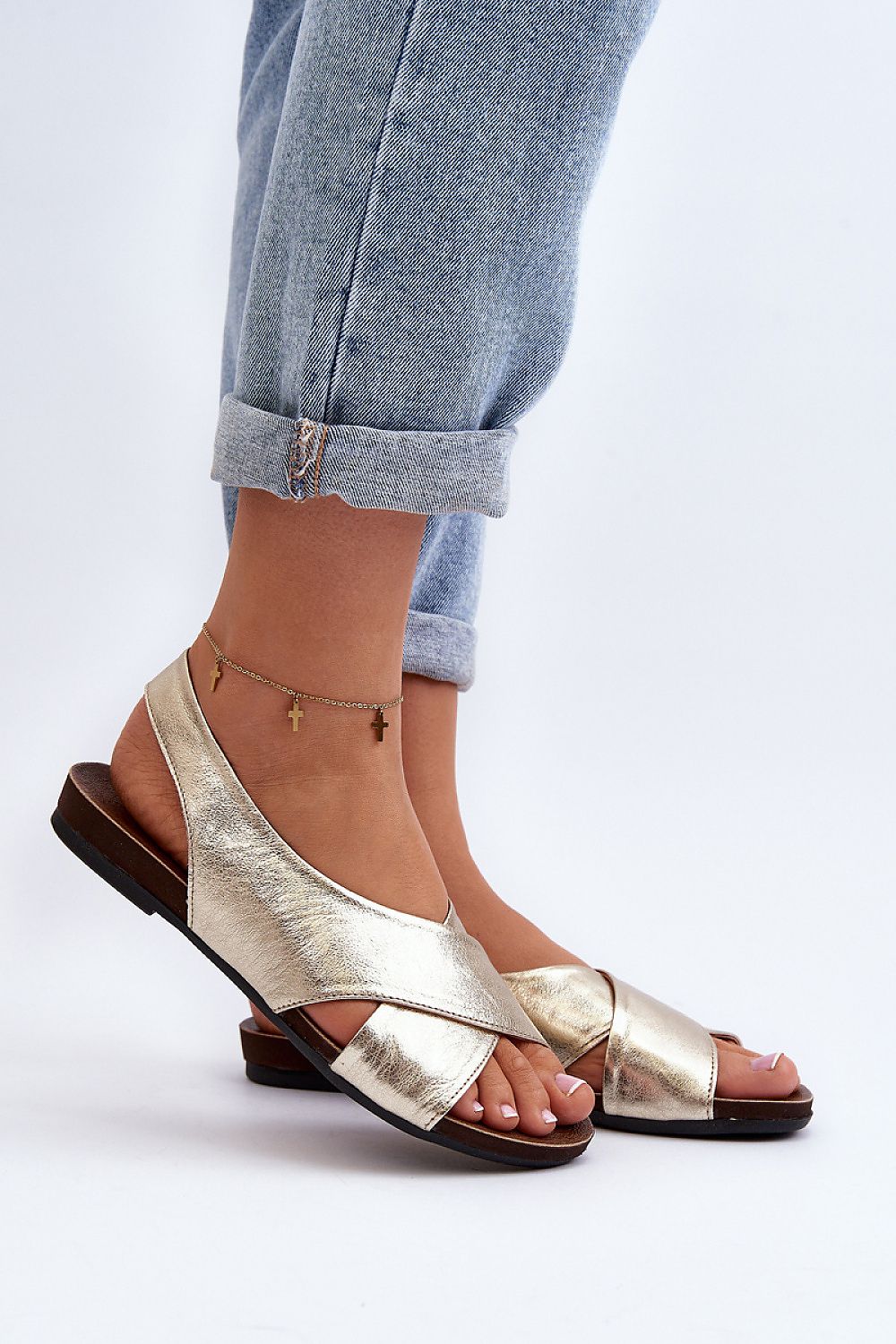 Woman wearing Talmea Soft-Strap Leather Sandals in metallic gold, paired with rolled-up jeans, showcasing open toe and heel design.