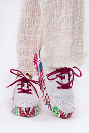 Lurevynn patterned platform sport shoes in white with colorful floral sole and red laces, worn with cream pants, showcasing versatility and style.