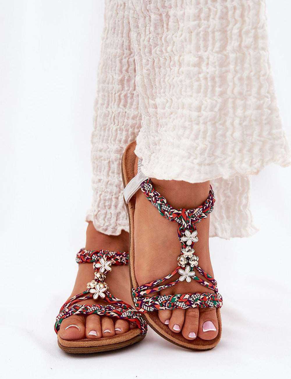 Woman wearing Zirellia Woven Flat Sandals with shimmering zircons and embellished straps, showcasing summer fashion.