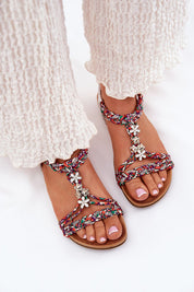 Person wearing Zirellia Woven Flat Sandals with colorful braided straps and floral embellishments, perfect for summer.