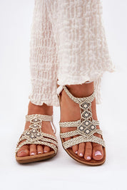 Woman wearing braided flat summer sandals with metallic accents and soft suede-like insole, perfect for warm-weather outings.