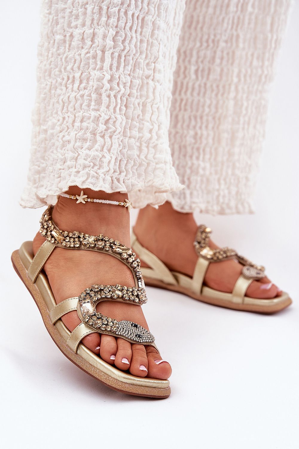 Nevalia Sandals with Crystal Snake Detail, featuring eco-leather and sequin-trimmed sole, worn with white pants, perfect for summer style.