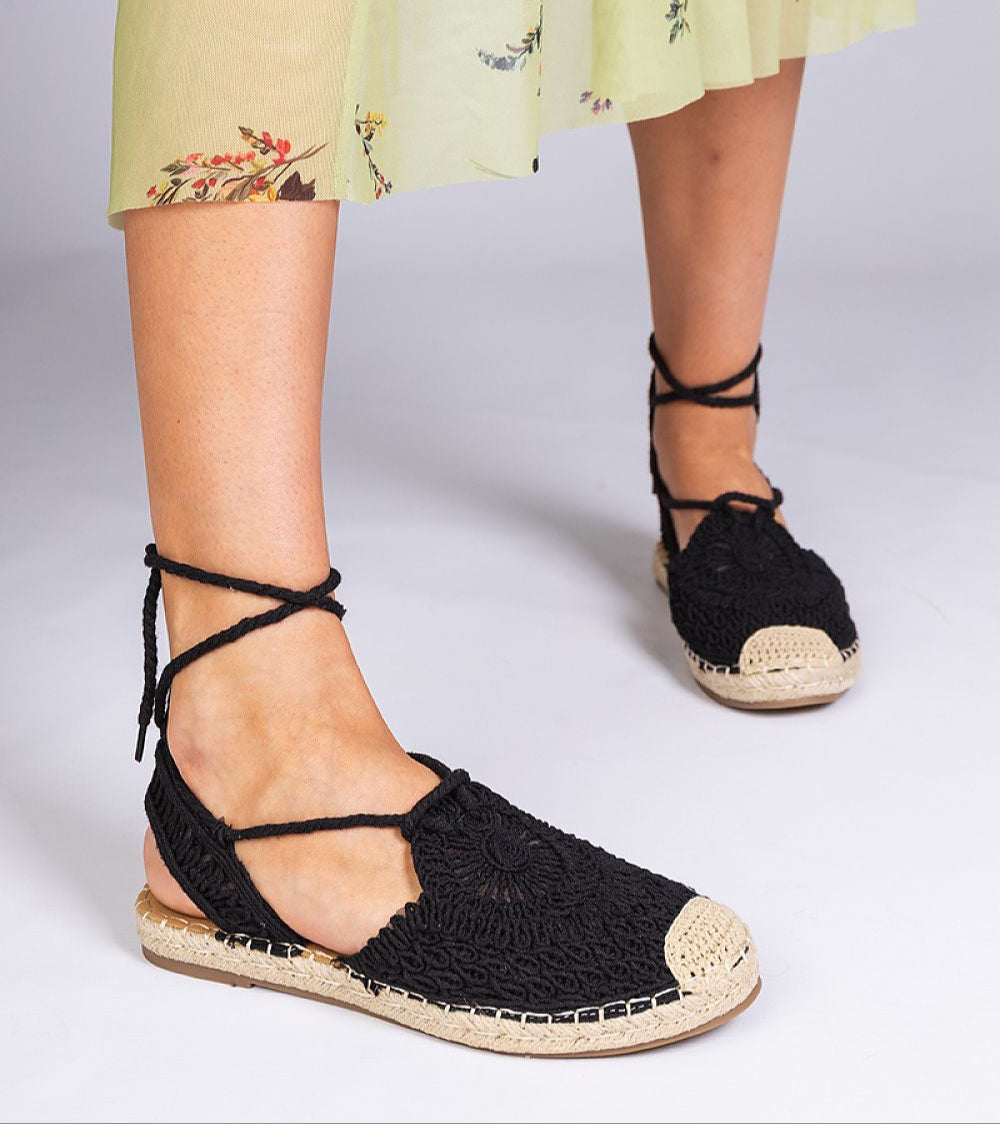 Black Serella Espadrille Sandals with braided sole, perfect for summer. Paired with a floral sundress, ideal for casual outings.
