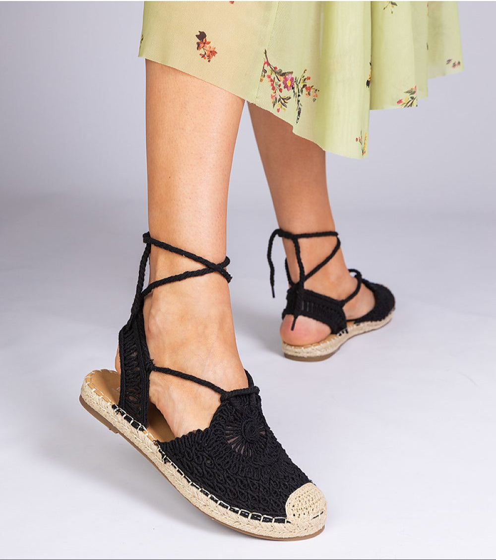 Woman wearing Serella Espadrille Sandals with a braided sole and black fabric, styled with a floral skirt for a summer look.
