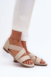 Model wearing Zirella Elastic Strap Sandals in beige eco-leather with elastic strap and soft insole, paired with white pants.