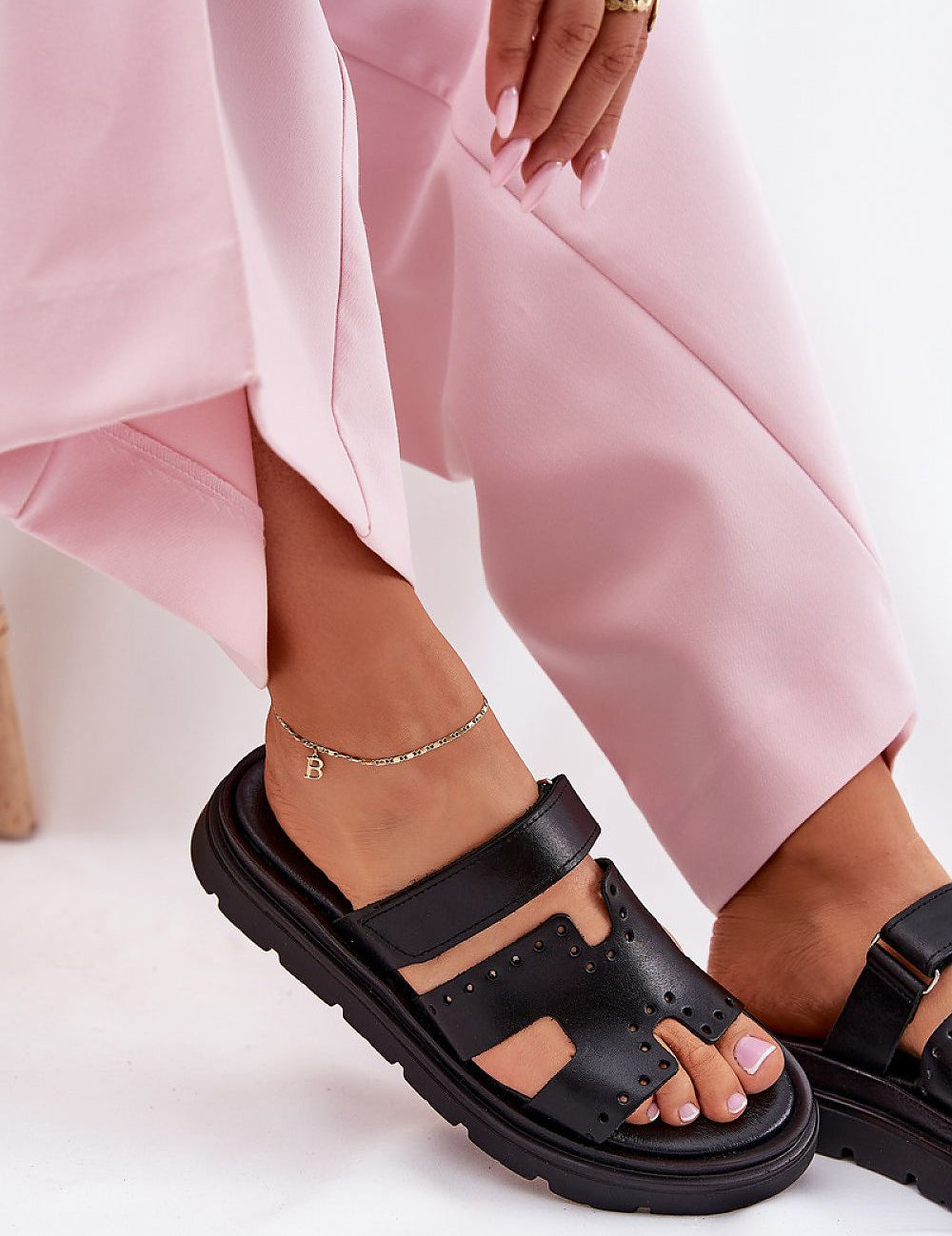 Woman wearing Mavena Platform Strap Sandals in black leather with pink trousers, showcasing stylish summer footwear and comfort.