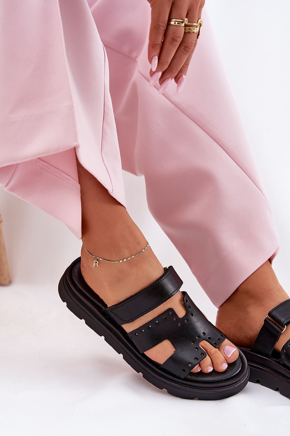 Woman wearing Mavena Platform Strap Sandals in black leather with pink trousers, showcasing stylish summer footwear and comfort.