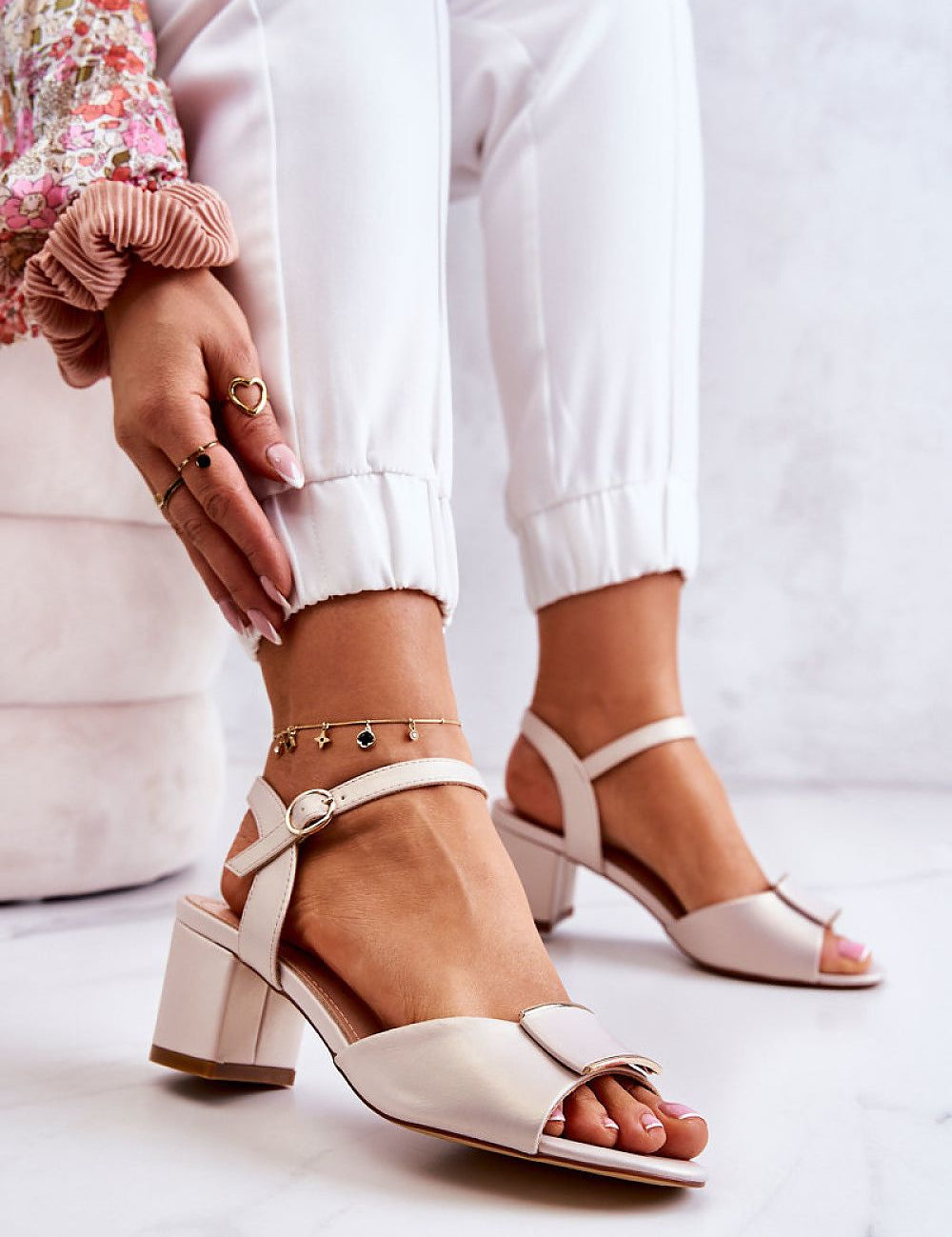 Ernara Heel-Strap Sandals featuring a decorative front accent, slim ankle strap with metal buckle, and elegant low pillar-style heel.