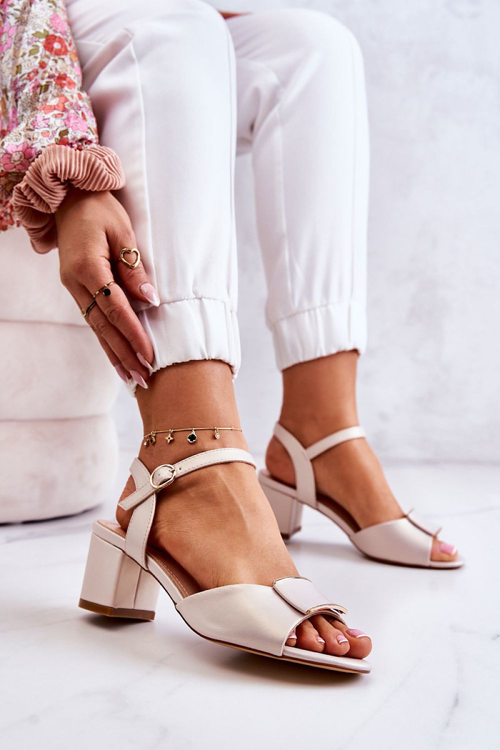 Ernara Heel-Strap Sandals featuring a decorative front accent, slim ankle strap with metal buckle, and elegant low pillar-style heel.