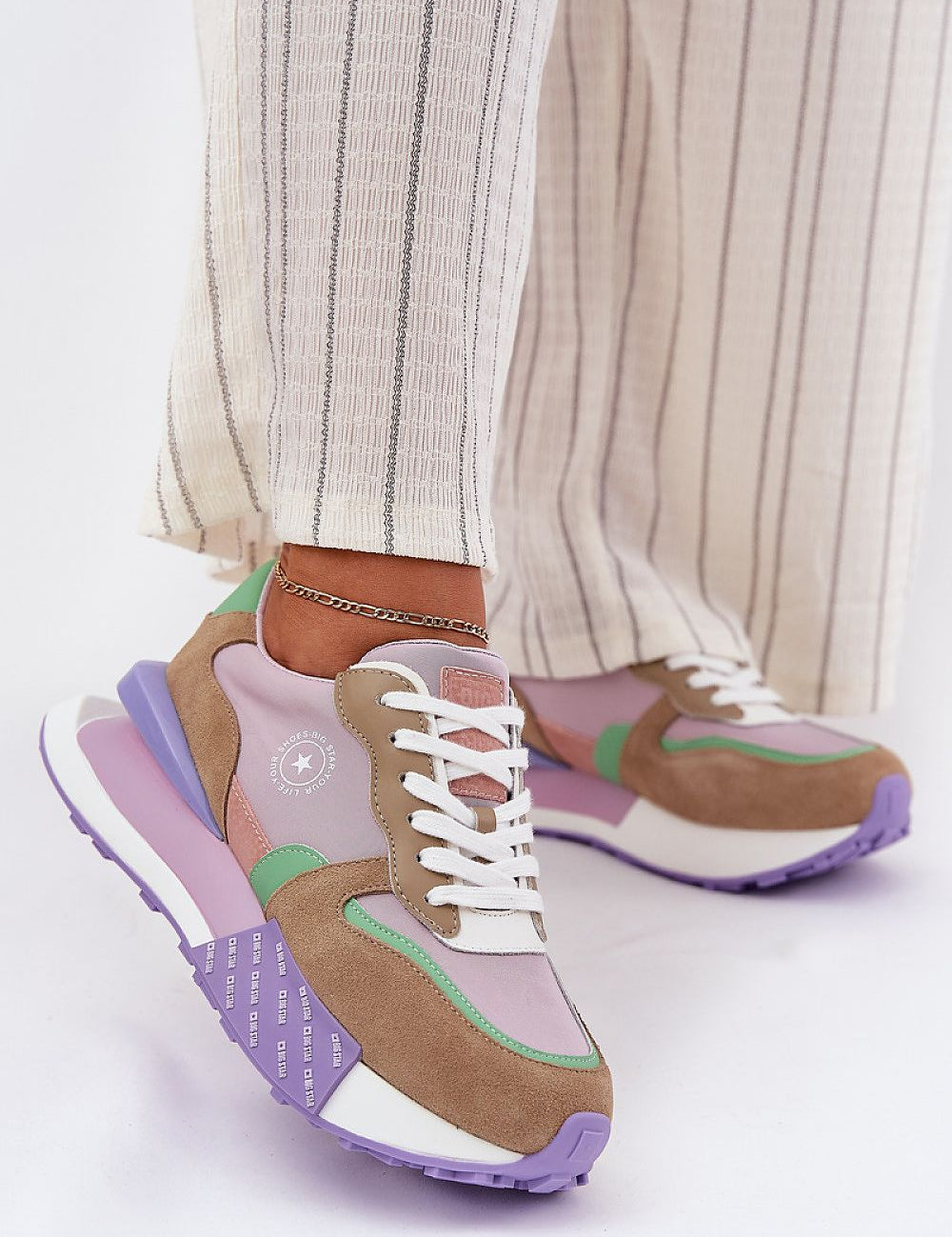 Colorful Velzora suede texture sneakers with platform soles, worn with striped pants, perfect for everyday comfort and style.