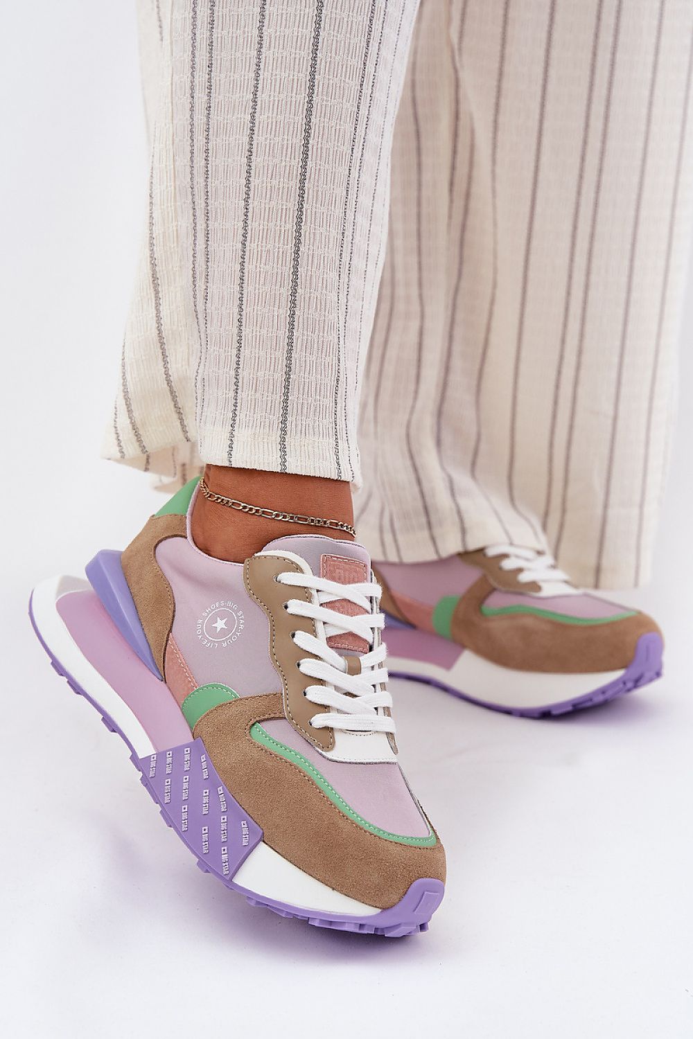 Colorful Velzora suede texture sneakers with platform soles, worn with striped pants, perfect for everyday comfort and style.