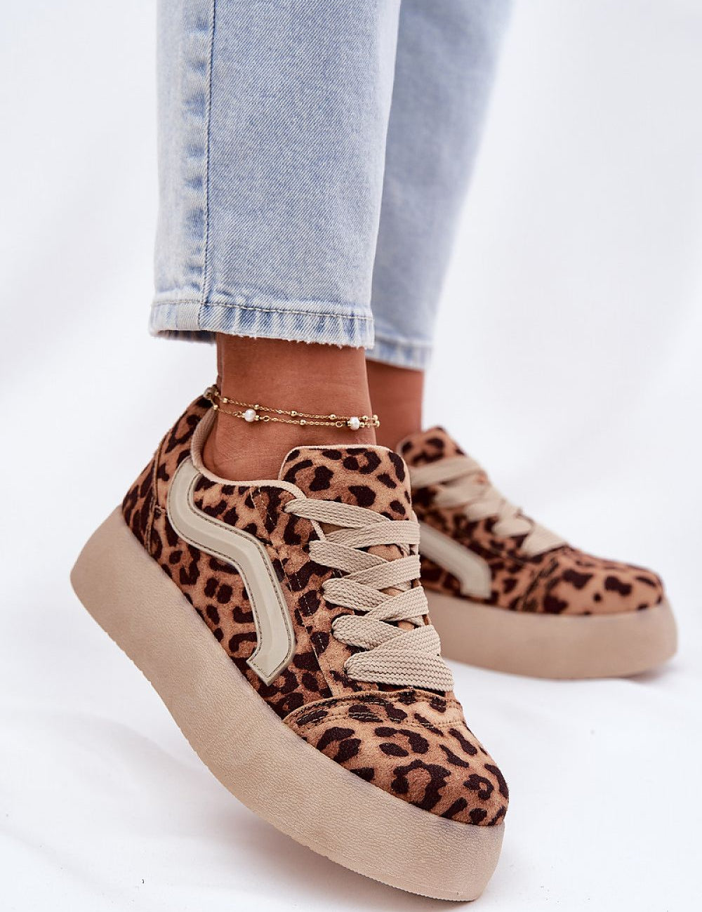Leopard print suede platform sneakers with rounded toe and platform sole, styled with light jeans and ankle bracelet for a chic look.