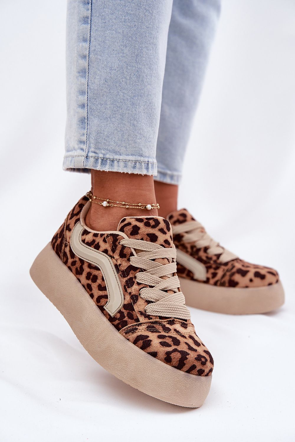 Leopard print suede platform sneakers with rounded toe and platform sole, styled with light jeans and ankle bracelet for a chic look.