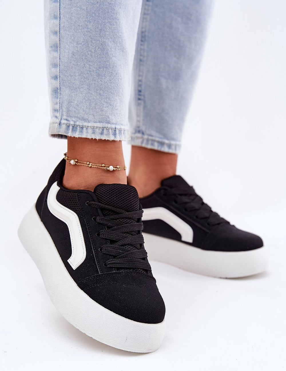 Ravelin Suede Platform Sneakers in black eco-suede with white accents, worn with light denim jeans, showcasing their rounded toe and platform sole.