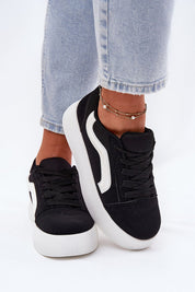 Black suede platform sneakers with white sole, worn with light-wash denim jeans, showcasing versatile and chic footwear style.