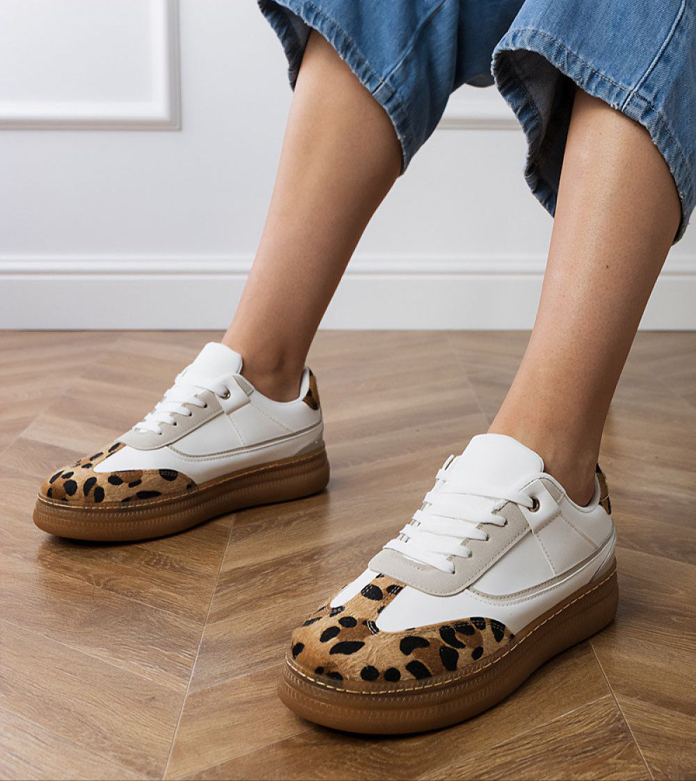 Woman wearing Merisse Panther Accent Sneakers with white profile and panther print, showcasing elevated platform on wooden floor.