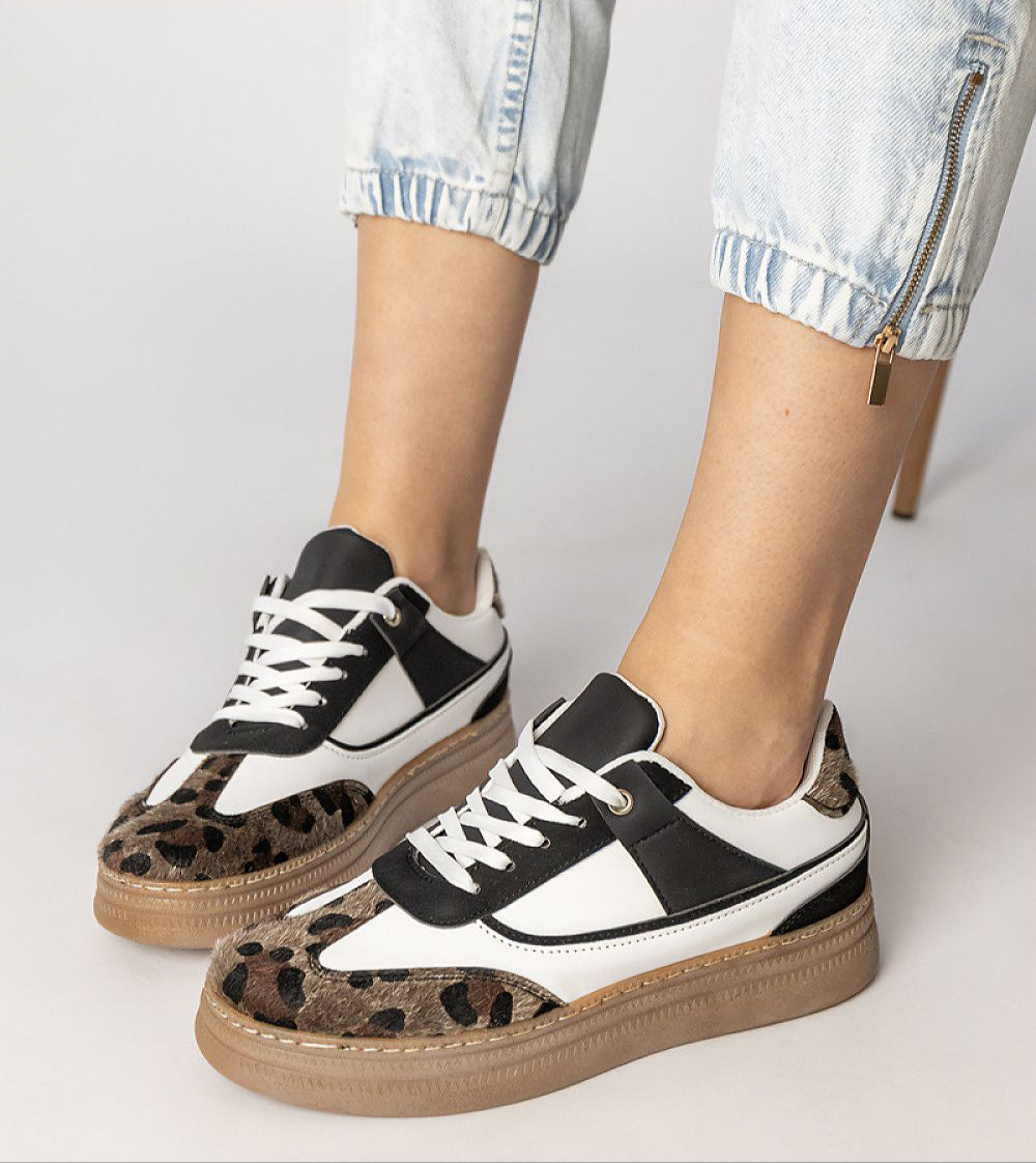 Woman wearing Merisse Panther Accent Sneakers with white profile and panther print, elevated platform, paired with casual denim jeans.