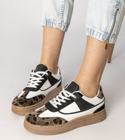 Woman wearing Merisse Panther Accent Sneakers with white profile and panther print, elevated platform, paired with casual denim jeans.
