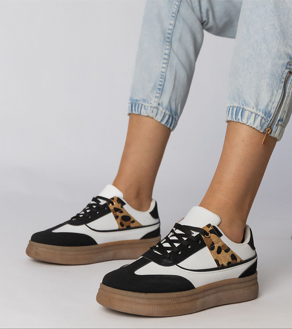 Woman wearing Merisse Panther Accent Sneakers with panther print detail and heightened platform, styled with light denim jeans.