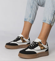 Woman wearing Merisse Panther Accent Sneakers with panther print detail and heightened platform, styled with light denim jeans.