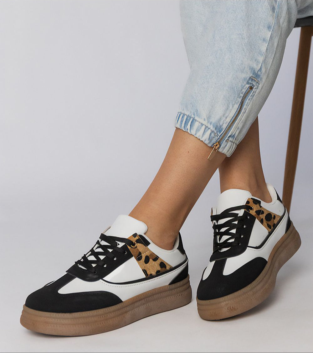 Person wearing Merisse Panther Accent Sneakers with panther print detail and platform soles, paired with light denim jeans.