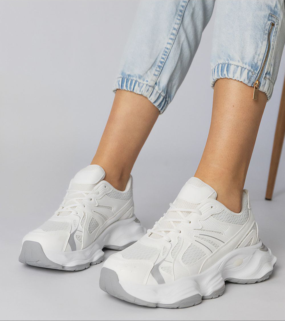 White Thareen platform trainers with chunky sole and faux leather texture, worn with blue jeans for an urban look.