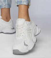 Person wearing white Thareen Platform Trainers with chunky sole and faux leather finish.