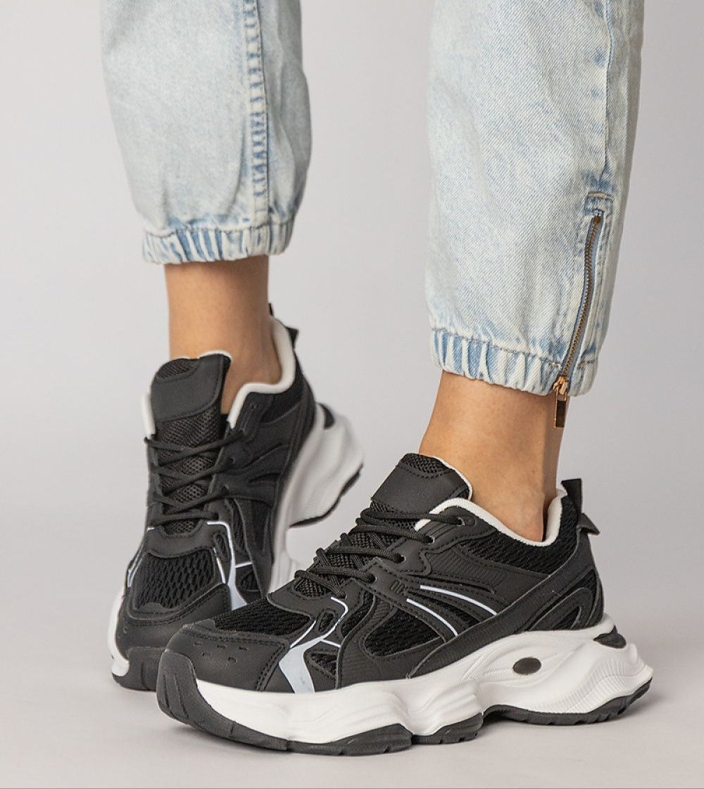 Black Thareen Platform Trainers with chunky sole and embossed faux leather, worn with rolled jeans. Urban fashion sneakers for daily comfort.