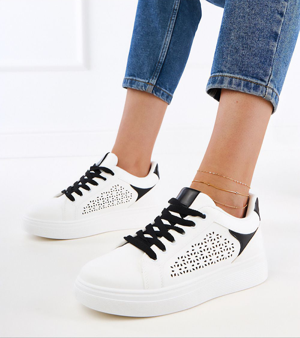 Stylish white platform sneakers with black accents and perforated design worn with cropped jeans.
