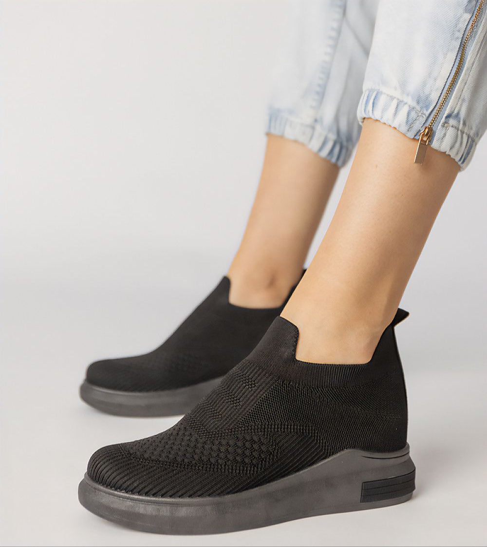 Black Shadowknit Slip-On Sock Sneakers with sculpted silhouette and platform sole, worn with light denim joggers.
