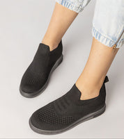 Black slip-on sock sneakers with stretch-knit upper and platform sole, offering a minimalist look for urban style on white background.