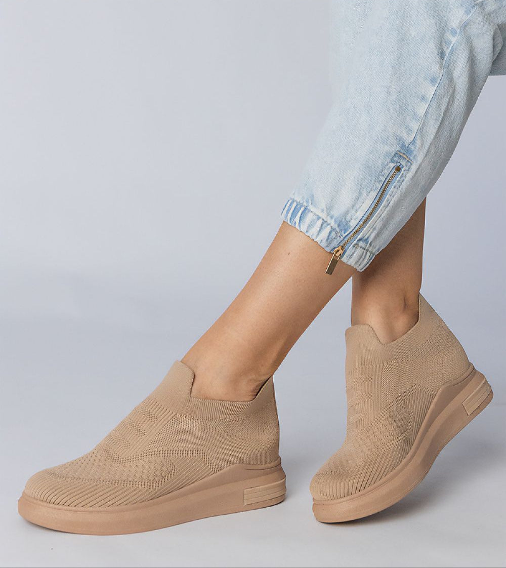 Beige Shadowknit slip-on sock sneakers with a sculpted silhouette and stretch-knit upper, paired with light blue denim pants.