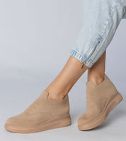 Beige Shadowknit slip-on sock sneakers with a sculpted silhouette and stretch-knit upper, paired with light blue denim pants.
