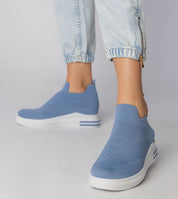 Person wearing blue Shadowknit Slip-On Sock Sneakers with white platform sole and denim pants, showcasing a minimalist urban style.