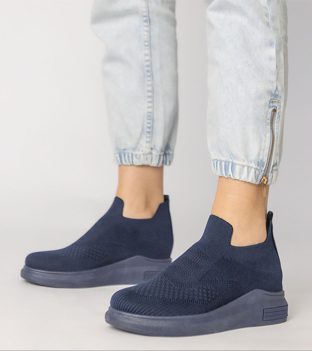 Shadowknit Slip-On Sock Sneakers in navy, featuring a stretch-knit upper and platform sole, styled with light-wash jogger pants.